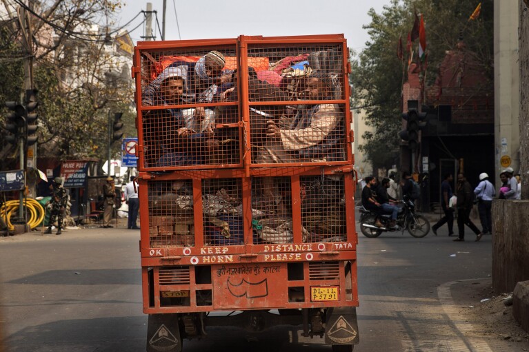 ARQUIVO - Um grupo de muçulmanos amontoados na traseira de uma caminhonete após violentos confrontos em uma localidade em Nova Delhi, Índia, em 26 de fevereiro de 2020. As tensões entre hindus e muçulmanos na Índia não são novas, mas pioraram sob o primeiro-ministro Ministro Narendra Modi.  (Foto AP / Rajesh Kumar Singh, arquivo)