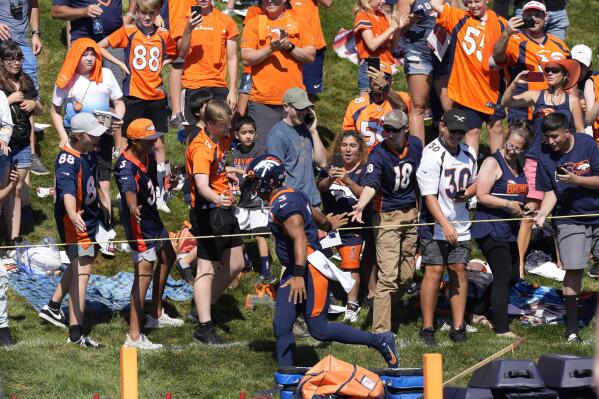 Denver Broncos quarterback Russell Wilson runs along the rope line to greet fans during the opening session of the NFL football team's training camp Wednesday, July 27, 2022, in Centennial, Colo. (AP Photo/David Zalubowski)