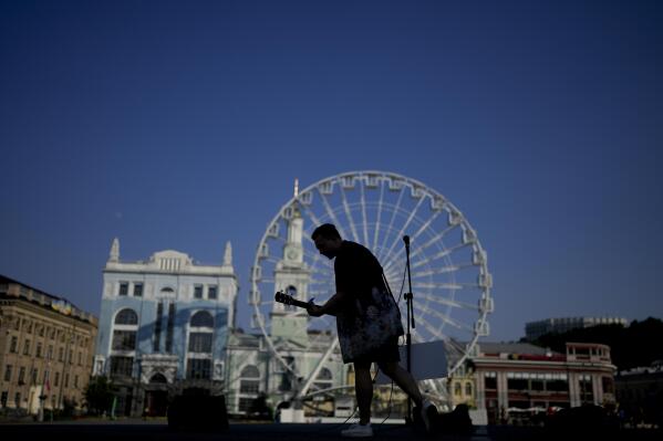 A street musician performs in Kyiv, Ukraine, Friday, June 10, 2022. With war raging on fronts to the east and south, the summer of 2022 is proving bitter for the Ukrainian capital, Kyiv. The sun shines but sadness and grim determination reign. (AP Photo/Natacha Pisarenko)