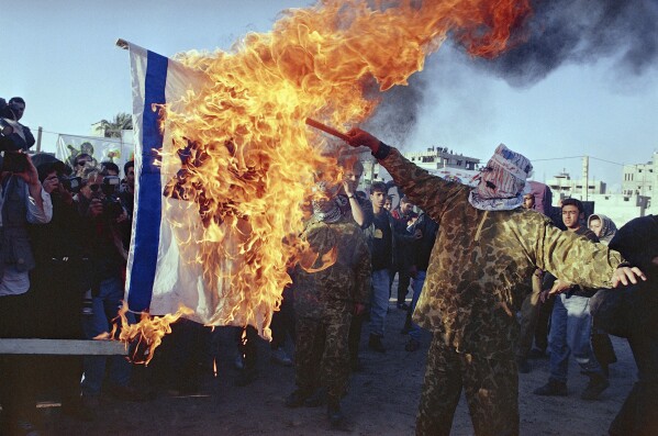 FILE - Masked Islamic activists burn an Israeli flag at a mass rally held, Nov. 26, 1994, in Gaza City held a week after Palestinian policemen and Hamas supporters shot at each other in Gaza. (AP Photo/Nabil Judah, File)