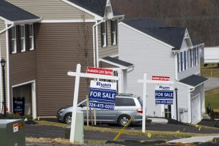 Model homes and for sale signs line the streets as construction continues at a housing plan in Zelienople, Pa., Wednesday, March 18, 2020. U.S. home sales jumped in February to their highest level in 13 years, a trend that will almost certainly be reversed as the viral outbreak keeps more people at home.  (AP Photo/Keith Srakocic)