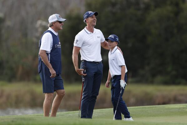 Henrik Stenson, center, laughs with his son Karl Stenson on the 14th hole during the first round of the PNC Championship golf tournament Saturday, Dec. 18, 2021, in Orlando, Fla. (AP Photo/Scott Audette)