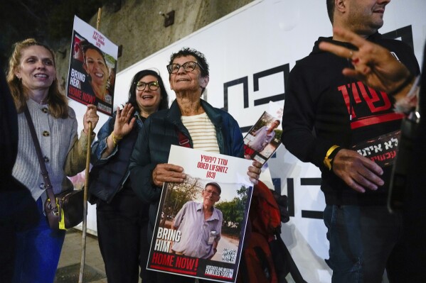 FILE - Yocheved Lifshitz, 85, center, who was released from captivity after being held hostage by Hamas, holds a photo of her husband Oded during a protest calling for the release of all hostages still held in the Gaza Strip, on Nov. 28, 2023, in Tel Aviv, Israel. An Associated Press review of Hamas instruction manuals shows the group planned ahead of time to target civilians. (AP Photo/Ariel Schalit, File)