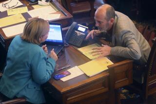 FILE - Kansas state Sens. Caryn Tyson, left, R-Parker, and Mark Steffen, right, R-Hutchinson, confer, at the Statehouse in Topeka, Kan., Feb. 4, 2021. Steffen, also is a physician, said Wednesday, Jan. 26, 2022, he's been under investigation by the state medical board for more than a year over his public comments about COVID-19, dating back even to late 2020, before he was in the Legislature. He also said he's written prescriptions for the parasitic worm treatment ivermectin as a treatment for COVID-19. (AP Photo/John Hanna, File)