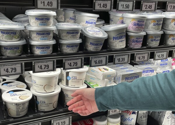 Stuart Dryden reaches for a store-label cream cheese at a grocery store on Wednesday, Feb. 21, 2024, in Arlington, Va. Dryden is aware of big price disparities between branded products and their store-label competitors, which he now favors. (AP Photo/Chris Rugaber)