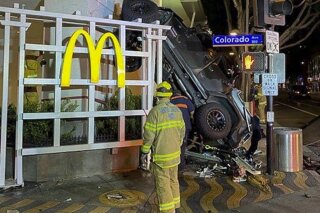 In this early Sunday, Feb. 23, 2020 photo released by the Santa Monica Fire Department shows a vehicle that plunged into the sidewalk in Santa Monica, Calif. A man was hospitalized after driving his Jeep off the the sixth floor of a Los Angeles-area parking garage. Responding officers found the destroyed vehicle up against a McDonald's restaurant across the street from the public parking structure. The 20-year-old driver was conscious and speaking with officers when they arrived. He was transported in critical condition. Fire officials say two passengers inside the Jeep were able to jump out before it went off the roof. The cause of the crash is under investigation. (Santa Monica Fire Department via AP)