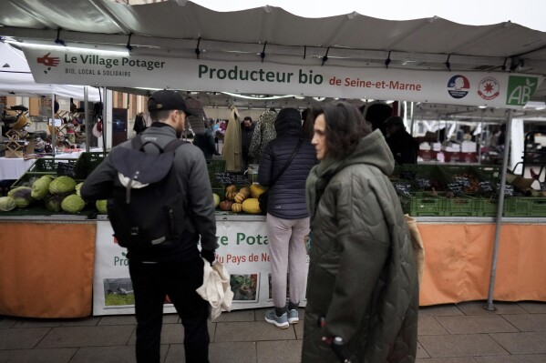 People shop at an organic food seller in an open air market in Fontainebleau, south of Paris, France, Friday, Feb. 2, 2024. European farmers and households are both hurting these days because of multiple factors, including persistent inflation, high interest rates and volatile energy prices. (AP Photo/Thibault Camus)