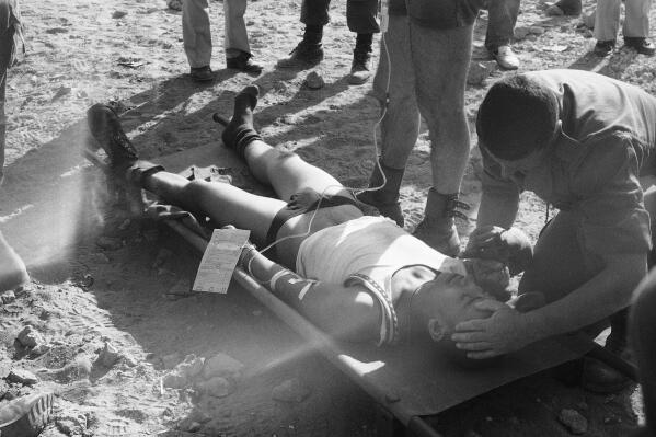 FILE - A wounded French soldier is attended to by a doctor after he was injured in a huge car bomb attack at a building housing members of the French contingent of the peacekeeping forces in Beirut, Oct. 23, 1983. Judicial authorities in France have sent a judicial request to Lebanon's prosecution, Wednesday, March 8, 2023 asking them to detain two people suspected in being involved in a 1983 bombing in Beirut that killed dozens of French troops, judicial officials said Wednesday. (AP Photo/Nagi, File)