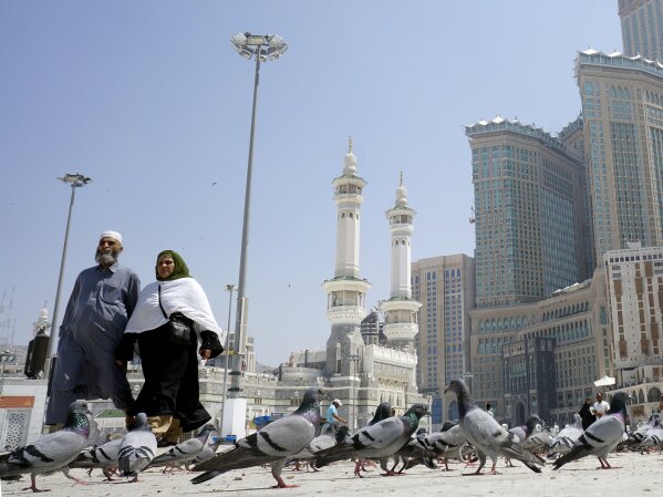 Muslim worshippers walk past pigeons after the noon prayers outside the Grand Mosque, in the Muslim holy city of Mecca, Saudi Arabia, Saturday, March 7, 2020. Saudi Arabia announced there would be no spectators for sports competitions and games starting Saturday in order to combat the spread of the virus. The kingdom has taken unprecedented measures against the virus' spread, including halting all pilgrimage in Mecca, Islam's holiest site.  (AP Photo/Amr Nabil)