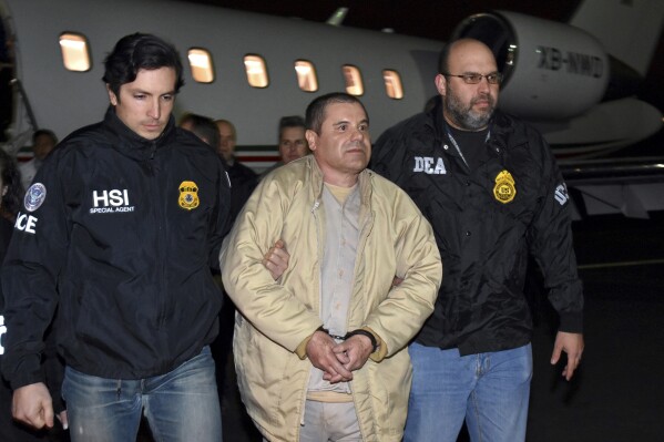 FILE - Authorities escort Joaquin "El Chapo" Guzman from a plane to a waiting caravan of SUVs at Long Island MacArthur Airport, in Ronkonkoma, N.Y., Jan. 19, 2017. Guzmán wrote a letter to District Court Judge Brian M. Cogan in the Eastern District of New York in late March 2024, claiming he cannot get phone calls or visits in the maximum security U.S. prison where he is serving a life sentence. (U.S. law enforcement via AP, File)