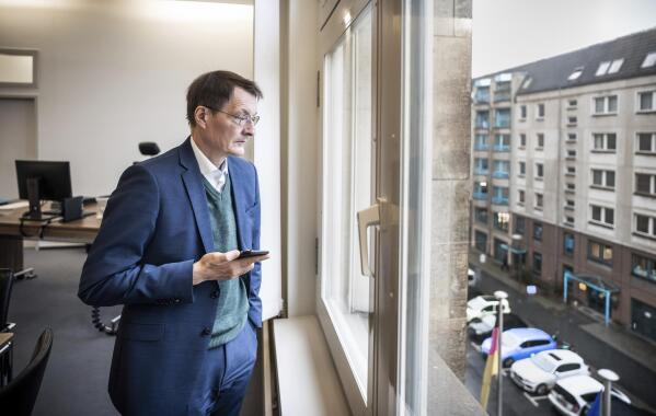 Karl Lauterbach, Federal Minister of Health, looks out of his office shortly before his participation in the video conference of the German government's expert council on the Corona pandemic in Berlin, Germany, Tuesday, Jan. 4, 2022. (Michael Kappeler/dpa via AP)