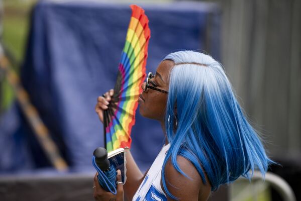 Sydney Porter waves a rainbow fan while watching Leslie Carter perform during the Dallas Southern Pride Juneteenth Unity Weekend Celebration at The Cove Aquatic Center in Dallas, Saturday, June 17, 2023. From a block party in New York City to a movie screening outside of Denver, groups across the U.S. have found ways to merge Pride month and Juneteenth celebrations. (AP Photo/Emil T. Lippe)