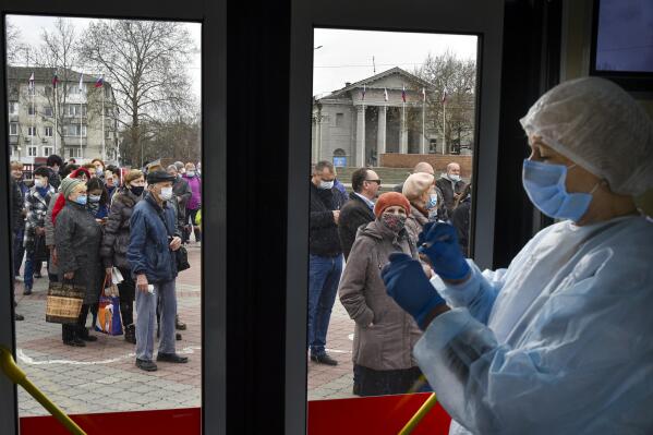 A Russian medical worker prepares a shot of Russia's Sputnik V coronavirus vaccine as people wearing face masks to protect against coronavirus queue to get a shot of Russia's Sputnik V coronavirus vaccine in a mobile vaccination center in Simferopol, Crimea, Tuesday, April 13, 2021. Alexander Dragan, a data analyst who has been tracking vaccination in the Russian regions, says Russia is currently vaccinating 200,000-205,000 people a day. In order to immunize 30 million people by mid-June, it needs to be nearly double that: "We need to start vaccinating 370,000 people a day, like, beginning tomorrow," Dragan told the AP. (AP Photo/Alexander Polegenko)