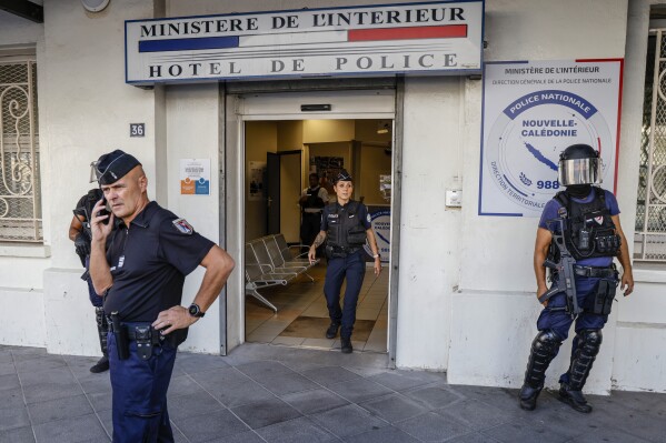 FILE - Police wait for the arrival of French President Emmanuel Macron at the central police station in Noumea, New Caledonia, Thursday, May 23, 2024. Police in the restive French Pacific territory of New Caledonia on Wednesday June 19, 2024 rounded up eight people, including an independence leader, suspected of having had a guiding role in deadly violence that wracked the archipelago where Indigenous Kanak people have long sought to break free from France. (Ludovic Marin/Pool Photo via AP)