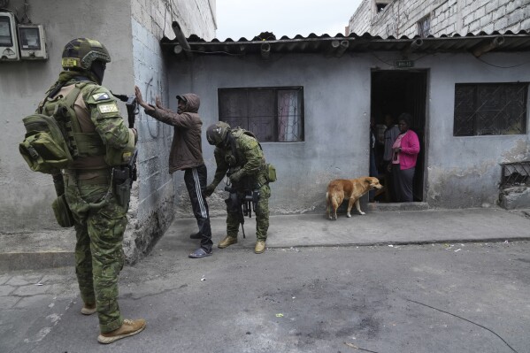 Soldiers stop and search a pedestrian for weapons as they patrol residential areas in northern Quito, Ecuador, Thursday, Jan. 11, 2024. President Daniel Noboa decreed Monday a national state of emergency due to a wave in crime, a measure that lets authorities suspend people's rights and mobilize the military. The government also imposed a curfew. (AP Photo/Dolores Ochoa)