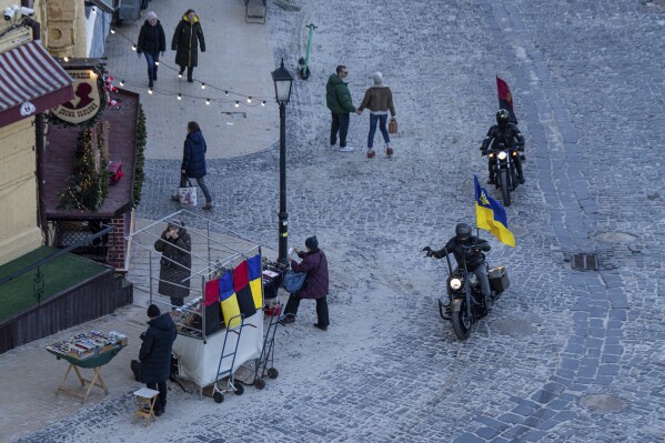 Motorcycle riders with Ukrainian and Ukrainian insurgent army flags pass in downtown Kyiv, Ukraine, Wednesday, Dec. 20, 2023. (AP Photo/Evgeniy Maloletka)