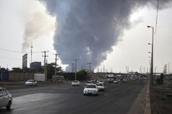 In this photo provided by Islamic Republic News Agency, IRNA, a black smoke rises in the sky as vehicles drive on the road after a massive explosion near the southern port city of Bandar Abbas, Iran, Saturday, April 26, 2025. (Mohammad Rasoul Moradi/IRNA via AP)