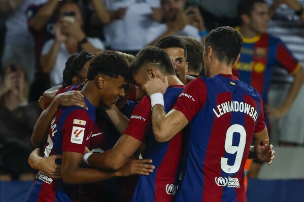 Barcelona players celebrate after Sevilla's Sergio Ramos scores an own goal past his goalkeeper during a Spanish La Liga soccer match between Barcelona and Sevilla, at the Olympic Stadium of Montjuic in Barcelona, Spain, Friday, Sept. 29, 2023. (AP Photo/Joan Monfort)
