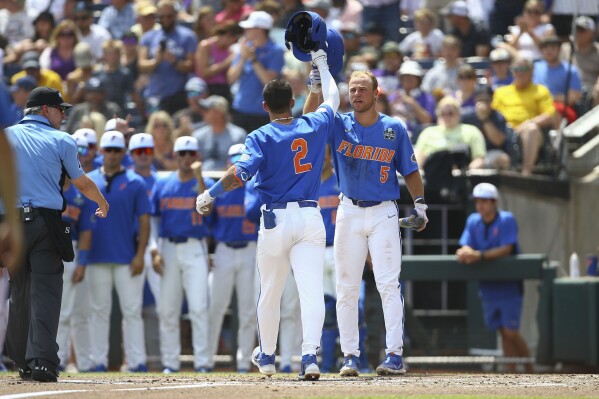 Florida outfielder Ty Evans (2) is greeted at the plate by Ben Nippolt (5) after his solo home run during the second inning of Game 2 of the NCAA College World Series baseball finals against LSU in Omaha, Neb., Sunday, June 25, 2023. (AP Photo/John Peterson)