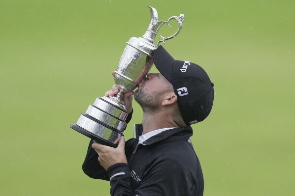 United States' Brian Harman kisses the trophy as he poses for the media holding the Claret Jug trophy for winning the British Open Golf Championships at the Royal Liverpool Golf Club in Hoylake, England, Sunday, July 23, 2023. (AP Photo/Kin Cheung)
