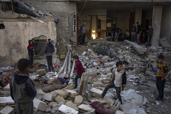Palestinians look at the destruction after an Israeli strike in Rafah, southern Gaza Strip, Friday, Dec. 29, 2023. (AP Photo/Fatima Shbair)