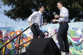 CORRECTS NAME FROM CHASTEN GLEZMAN TO CHASTEN BUTTGIEG FILE - In this May 20, 2019, file photo, Democratic presidential candidate Pete Buttigieg, the mayor of South Bend, Ind., left, is introduced by his husband Chasten Buttigieg, right, during a fundraiser at the Wynwood Walls, in Miami. Buttigieg knows firsthand the burden of six-figure student loan debt. He and his husband have loans of more than $130,000, placing them in the ranks of the 43 million Americans who owe federal student debt.(AP Photo/Lynne Sladky, File)