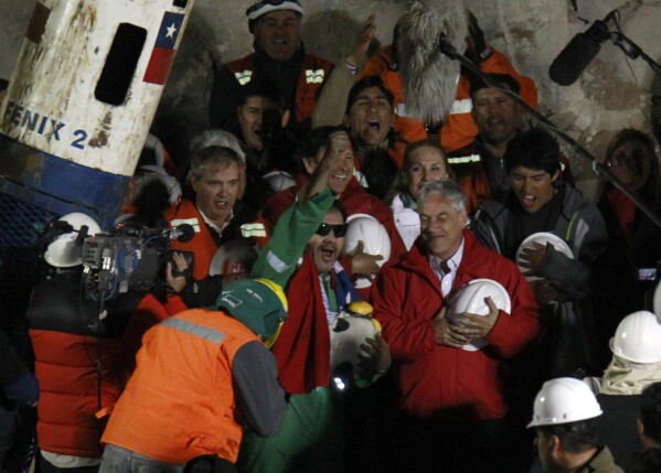 FILE - Luis Urzua, the last of the 33 miners to be rescued, center wearing green, celebrates next to Chile's President Sebastian Pinera after being pulled from the San Jose gold and copper mine near Copiapo, Chile. (AP Photo/Roberto Candia, File)