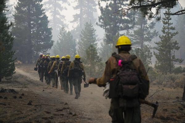 A hotshot crew from Tahoe Hotshots hikes along a trail in Meyers, Calif., Friday, Sept. 3, 2021. Fire crews took advantage of decreasing winds to battle a California wildfire near popular Lake Tahoe and were even able to allow some people back to their homes but dry weather and a weekend warming trend meant the battle was far from over. (AP Photo/Jae C. Hong)
