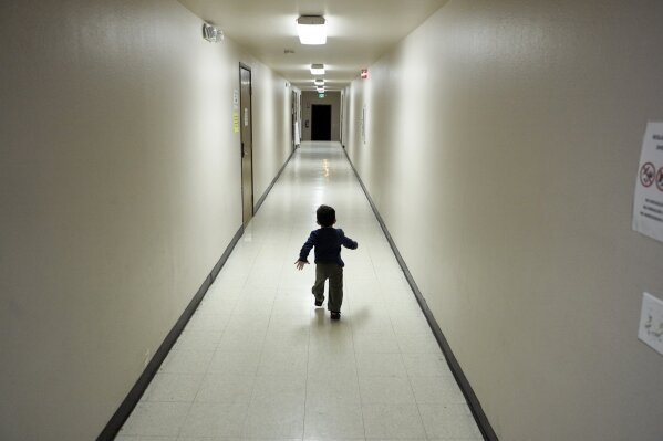 FILE - In this Dec. 11, 2018, file photo, an asylum-seeking boy from Central America runs down a hallway after arriving from an immigration detention center to a shelter in San Diego. A court-appointed committee has yet to find the parents of 628 children separated at the border early in the Trump administration. (AP Photo/Gregory Bull, File)