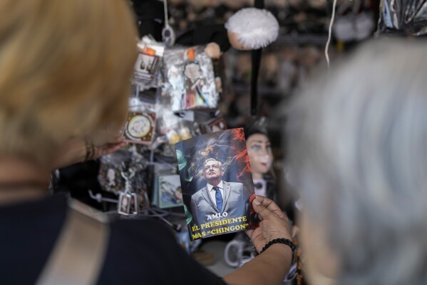 FILE - A shopper holds a postcard of Mexican President Andres Manuel Lopez Obrador written in Spanish. "AMLO, the coolest president" It is listed for sale outside the presidential palace in Mexico City on March 14, 2024. (AP Photo/Eduardo Verdugo, File)