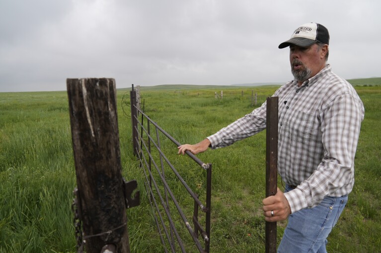 Brian Sprenger closes a gate Wednesday, June 21, 2023, in Sidney, Neb. (AP Photo/Brittany Peterson)