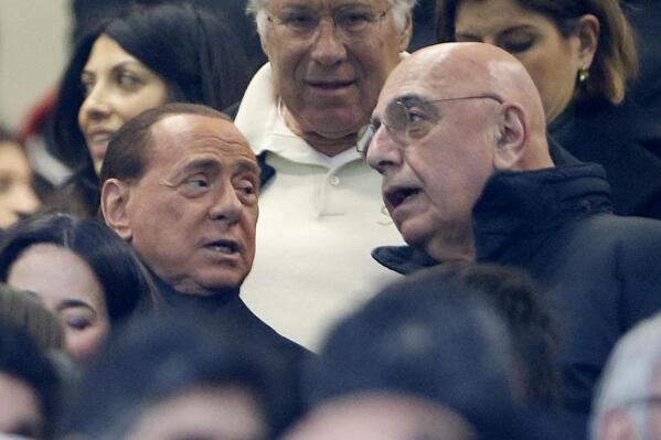 FILE - AC Milan president Silvio Berlusconi, left, is flanked by vice president Adriano Galliani during a Serie A soccer match between AC Milan and Inter Milan, at the San Siro stadium in Milan, Italy, on Jan. 31, 2016. Much of the attention will be focused off the field when Monza takes on defending champion AC Milan on Saturday, Oct. 22, 2022. There will be familiar faces in the directors’ box at San Siro as Silvio Berlusconi and Adriano Galliani return to the club they led to 29 trophies in 31 years.  (AP Photo/Luca Bruno, File)