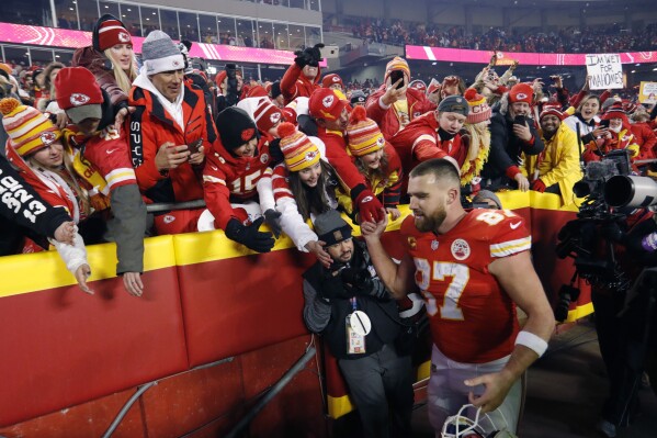 FILE - Kansas City Chiefs tight end Travis Kelce (87) celebrates with fans as he walks off the field after an NFL divisional round playoff football game against the Buffalo Bills, Sunday, Jan. 23, 2022, in Kansas City, Mo. Eager as the National Football League has been to cater to the recent public fixation with Taylor Swift and Travis Kelce, it’s certainly not taking any credit for creating the 