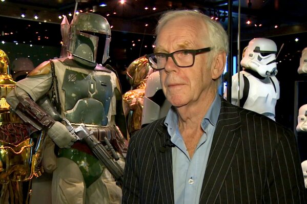 Jeremy Bulloch speaks in front of the costume he wore while playing Boba Fett in "Star Wars: Episode V – The Empire Strikes Back" and "Star Wars: Episode VI – Return of the Jedi" at the Star Wars Identities exhibition in London on July 26, 2017. Bulloch, the English actor who played Boba Fett in the original "Star Wars" trilogy, has died. His agents said in a statement that he died in a London hospital Thursday, Dec. 17, 2020, after years of suffering from Parkinson's disease. He was 75. (AP Photo)