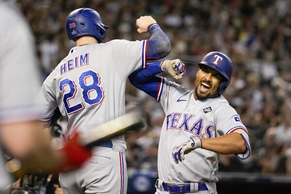 Texas Rangers' Marcus Semien, right, celebrates his three-run home run with Jonah Heim during the third inning in Game 4 of the baseball World Series against the Arizona Diamondbacks Tuesday, Oct. 31, 2023, in Phoenix. (AP Photo/Brynn Anderson)