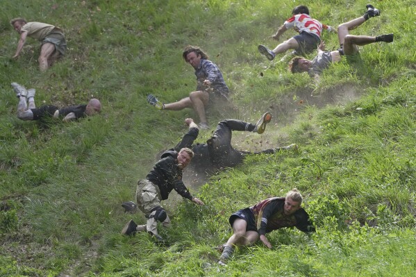 Participants compete in the men's downhill race during the Cheese Rolling contest at Cooper's Hill in Brockworth, Gloucestershire, May 29, 2023. (AP Photo/Kin Cheung)