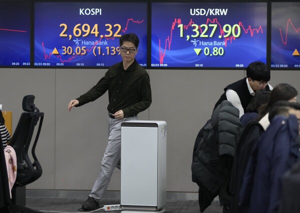 A currency trader passes by the screens showing the Korea Composite Stock Price Index (KOSPI), left, and the foreign exchange rate between U.S. dollar and South Korean won at the foreign exchange dealing room of the KEB Hana Bank headquarters in Seoul, South Korea, Friday, Feb. 23, 2024. Asian markets mostly gained on Friday after Nvidia delivered another blowout quarter, setting off a rally in other technology companies that carried Wall Street to another record high. (AP Photo/Ahn Young-joon)
