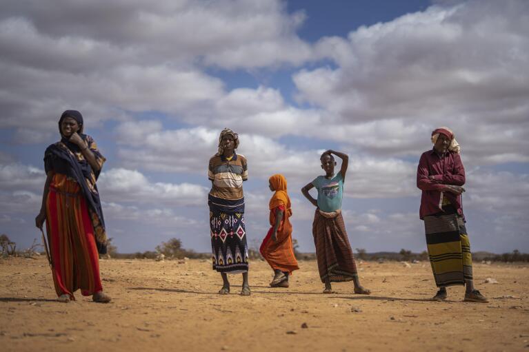 Men and women stand at a camp for displaced people on the outskirts of Dollow, Somalia, on Monday, Sept. 19, 2022.  Somalia is in the midst of the worst drought anyone there can remember. A rare famine declaration could be made within weeks. Climate change and fallout from the war in Ukraine are in part to blame. (AP Photo/Jerome Delay)