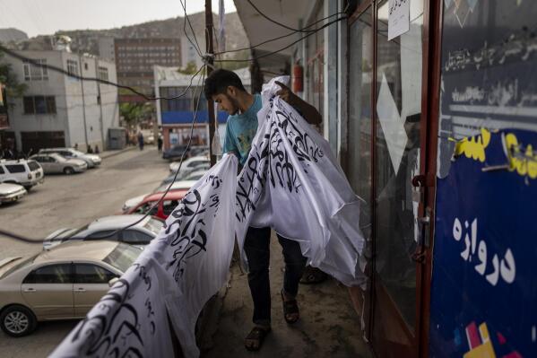 A worker collects newly hand printed Taliban flags in a workshop in Kabul's Jawid market, Afghanistan, Sunday, Sept. 12, 2021. The small flag shop, tucked away in the courtyard of a Kabul market, has documented Afghanistan’s turbulent history over the decades with its ever-changing merchandise. Now the shop is filled with white Taliban flags, emblazoned with the Quran's Muslim statement of faith, in black Arabic lettering. (AP Photo/Bernat Armangue)