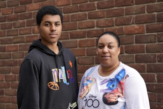 Stacy Williams stands with her son Davion, 15, in Detroit, Wednesday, Aug. 30, 2023. Davion wants to go to college. A counselor at his Detroit charter school in 2022 helped him visualize that goal, but he knows he’ll need more help to navigate the application process. So he was discouraged to learn the high school where he just began his sophomore year had laid off its college transition adviser – a staff member who provided extra help coordinating financial aid applications, transcript requests, campus visits and more. (AP Photo/Paul Sancya)