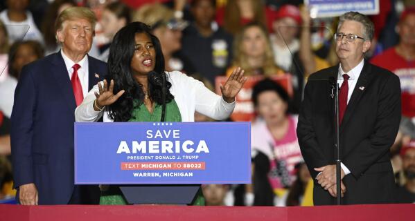 Former President Donald Trump, left, and Michigan Republican attorney general candidate Matt DePerno, right, listen as Michigan Republican secretary of state candidate Kristina Karamo addresses the crowd during a rally at the Macomb Community College Sports & Expo Center in Warren, Mich., Saturday, Oct. 1, 2022. With general election voting already underway in Michigan, Karamo stepped on stage as a warm-up act for Trump and hit hard on the main theme of her campaign -- repeating debunked assertions that the 2020 election was stolen from Trump. (Todd McInturf/Detroit News via AP)