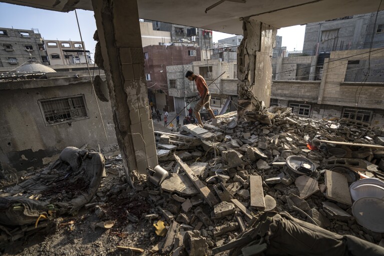 FILE - Palestinians look at the destruction after Israeli strikes on the Gaza Strip in Khan Younis on Now. 3, 2023. Entire generations of Palestinian families in the besieged Gaza Strip have been killed in airstrikes in the ongoing Hamas-Israel war. They include infants to elderly grandparents, killed in attacks the Israeli army says aim to root out the militant group from the densely populated coastal territory. (AP Photo/Fatima Shbair, File)