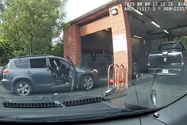 This still photo, from West Hartford Connecticut Police Department dashboard camera video on Aug 8, 2023, shows West Hartford Police officer Andrew Teeter attempting to apprehend Mike Alexander-Garcia in a stolen vehicle, left. (West Hartford Connecticut Police Department via AP)