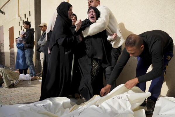 Palestinians mourn relatives killed in the Israeli bombardment of the Gaza Strip in front of the morgue in Deir al Balah, Sunday, Nov. 19, 2023. (AP Photo/Hatem Moussa)