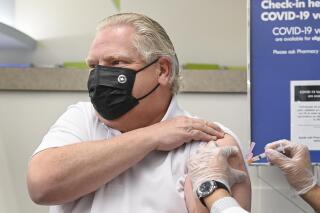Ontario Premier Doug Ford, left, receives the Astrazeneca-Oxford COVID-19 vaccine from pharmacist Anmol Soor at Shoppers Drug Mart during the COVID-19 pandemic in Toronto on Friday, April 9, 2021. (Nathan Denette/The Canadian Press via AP)