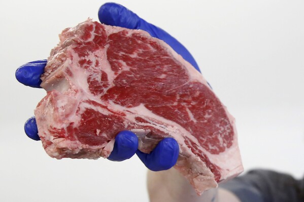 In this Wednesday, May 6, 2020, photo, Austin Black holds a porterhouse steak at Snider Bros. Meats, in Cottonwood Heights, Utah. (AP Photo/Rick Bowmer)