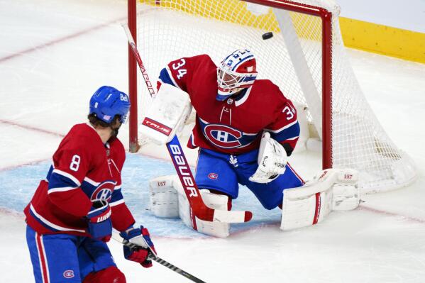 The puck flies into the net past Montreal Canadiens goaltender Jake Allen (34) on a goal by Vancouver Canucks' Elias Pettersson, not seen, as defenseman Ben Chiarot (8) looks on during the first period of an NHL hockey game, Monday, Nov. 29, 2021 in Montreal. (Paul Chiasson/The Canadian Press via AP)