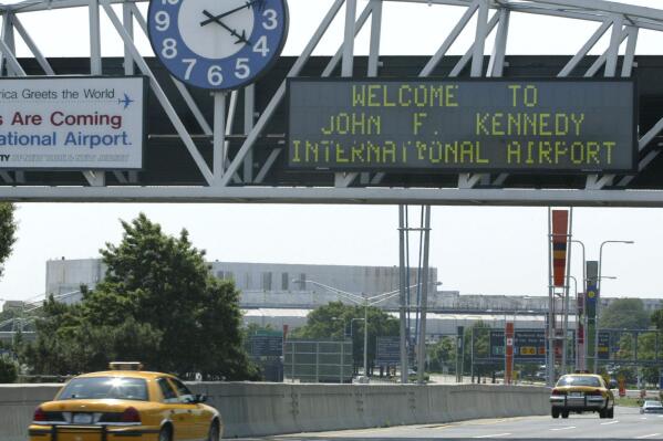 FILE - A clock at the entrance to JFK Airport in New York is pictured on Aug. 15, 2003. Officials are investigating a close call at the New York airport that happened Friday, Jan. 13, 2023, between a plane that was crossing a runway and another that was preparing for takeoff. (AP Photo/Stuart Ramson, File)