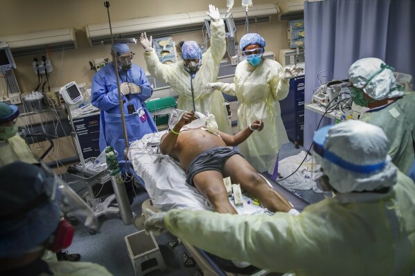 Nurses and doctors clear the area before defibrillating a patient with COVID-19 who went into cardiac arrest, Monday, April 20, 2020, at St. Joseph's Hospital in Yonkers, N.Y. The emergency room team successfully revived the patient. (AP Photo/John Minchillo)
