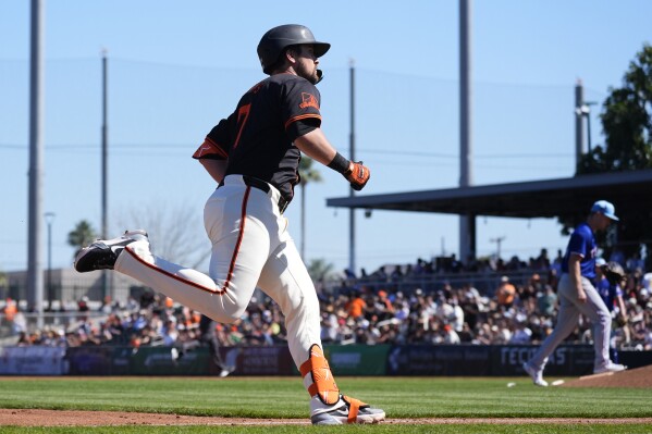 San Francisco Giants' J.D. Davis, left, rounds the bases after hitting a three-run home run against Texas Rangers starting pitcher Adrian Sampson, right, during the second inning of a spring training baseball game Friday, March 1, 2024, in Scottsdale, Ariz. (AP Photo/Ross D. Franklin)